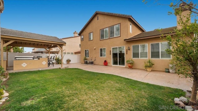 back of property with area for grilling, a gazebo, a lawn, and a patio