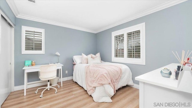 bedroom with crown molding, light hardwood / wood-style floors, and a closet