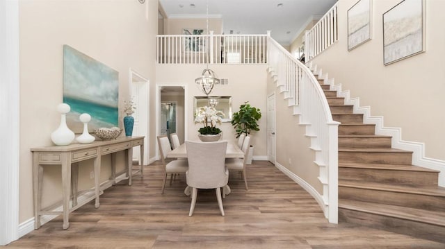 dining room with hardwood / wood-style floors, a notable chandelier, and a high ceiling