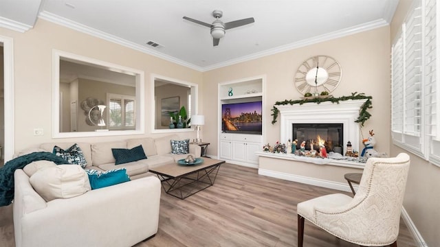 living room with ceiling fan, ornamental molding, wood-type flooring, and built in features