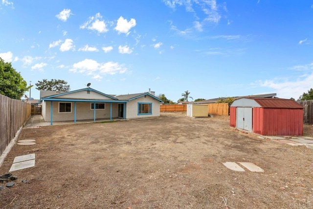 back of house with a storage unit