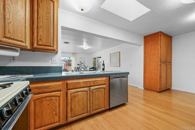 kitchen with a skylight, dishwasher, sink, black gas stove, and light hardwood / wood-style flooring