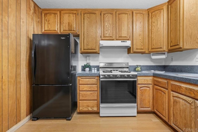 kitchen featuring gas range, light hardwood / wood-style flooring, and black fridge