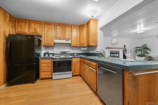 kitchen featuring sink, a textured ceiling, kitchen peninsula, light hardwood / wood-style floors, and black appliances