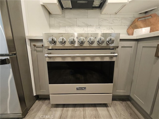 details featuring tasteful backsplash, gray cabinets, light hardwood / wood-style flooring, and appliances with stainless steel finishes