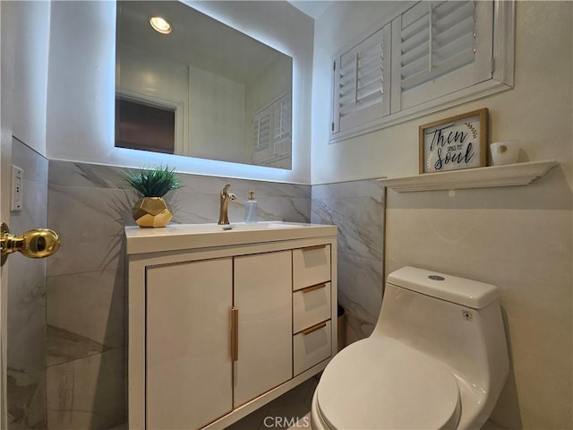 bathroom with vanity, toilet, and tile walls