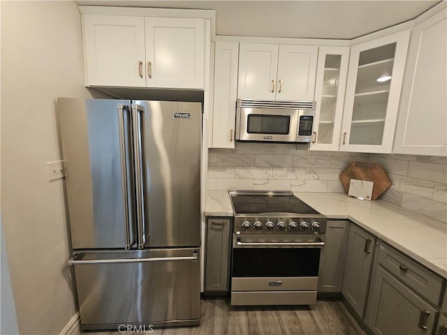 kitchen featuring high end appliances, gray cabinetry, white cabinets, and light stone counters