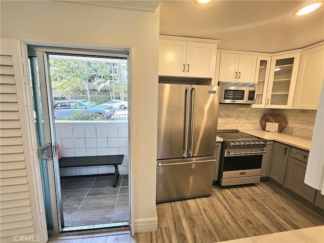 kitchen featuring tasteful backsplash, white cabinets, light hardwood / wood-style floors, and premium appliances