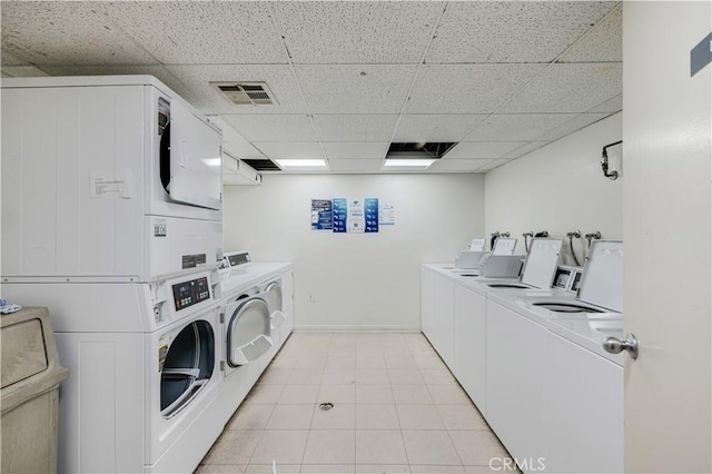 clothes washing area featuring washing machine and dryer, stacked washer and clothes dryer, and light tile patterned floors