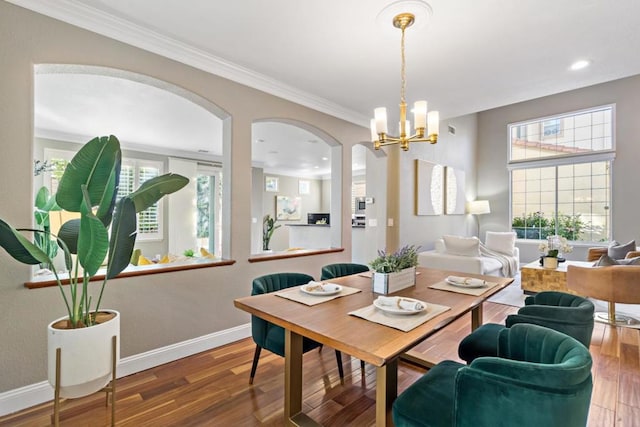 dining area with hardwood / wood-style flooring, crown molding, and an inviting chandelier