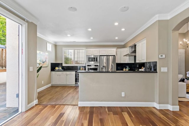 kitchen featuring wall chimney exhaust hood, white cabinetry, light hardwood / wood-style flooring, kitchen peninsula, and stainless steel appliances