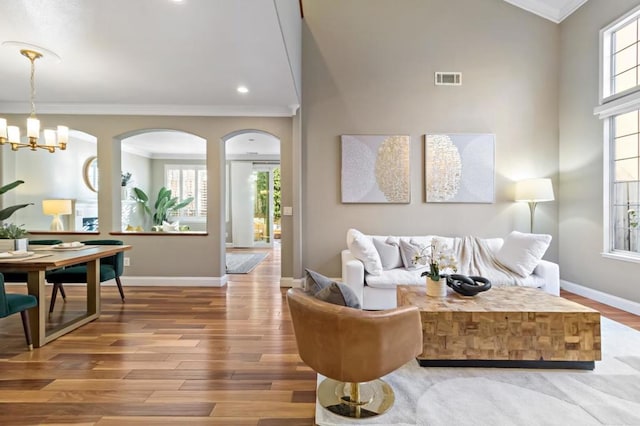 living room featuring ornamental molding, hardwood / wood-style floors, and an inviting chandelier