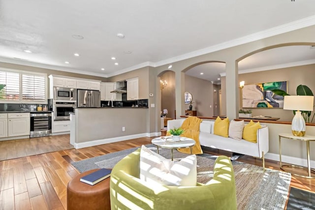 living room featuring wine cooler, crown molding, and light wood-type flooring