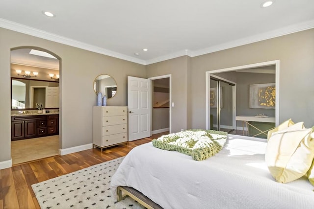 bedroom with hardwood / wood-style flooring, ornamental molding, sink, and ensuite bath