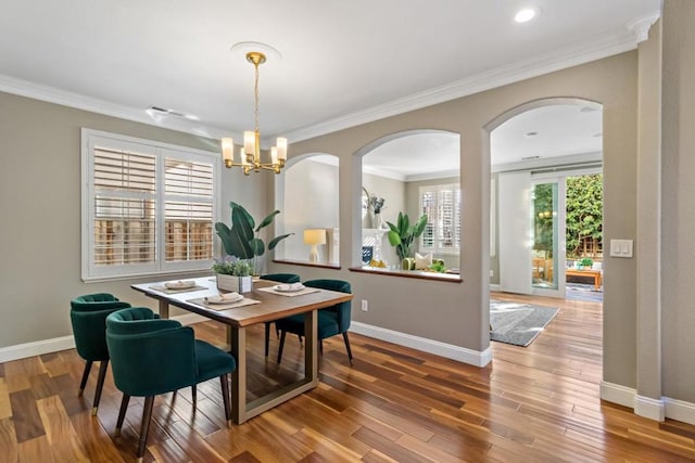 dining room with hardwood / wood-style floors, ornamental molding, and a chandelier