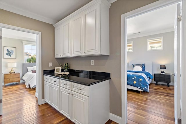 kitchen featuring white cabinetry, wood-type flooring, and ornamental molding