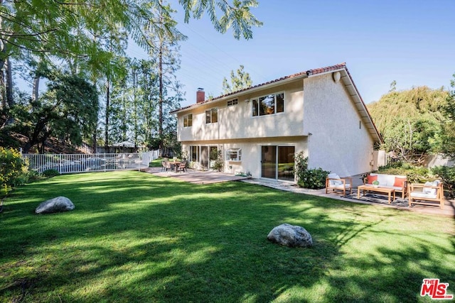 back of house featuring an outdoor living space, a patio area, and a lawn