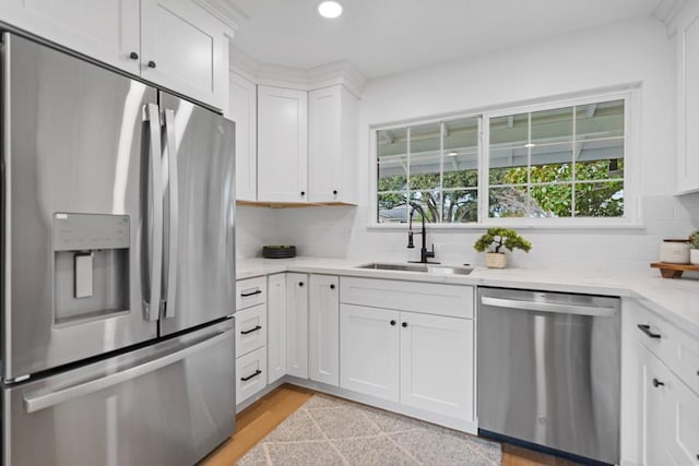 kitchen featuring stainless steel appliances, sink, tasteful backsplash, a healthy amount of sunlight, and white cabinets