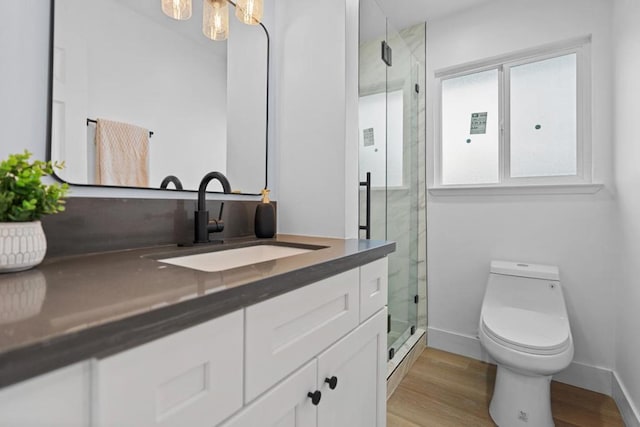 bathroom with wood-type flooring, toilet, an enclosed shower, and vanity