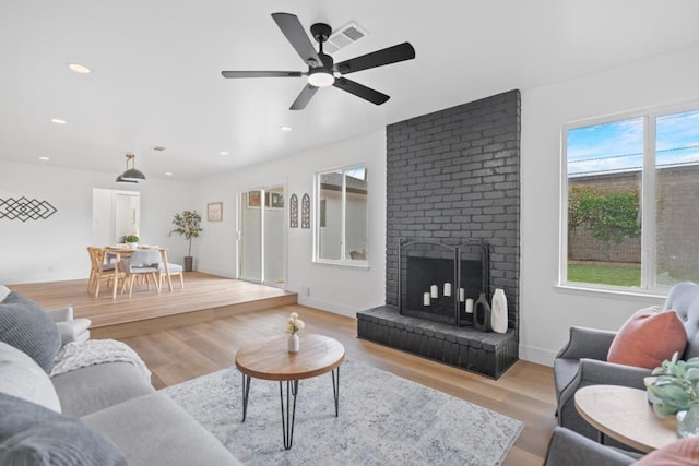 living room with a brick fireplace and light wood-type flooring