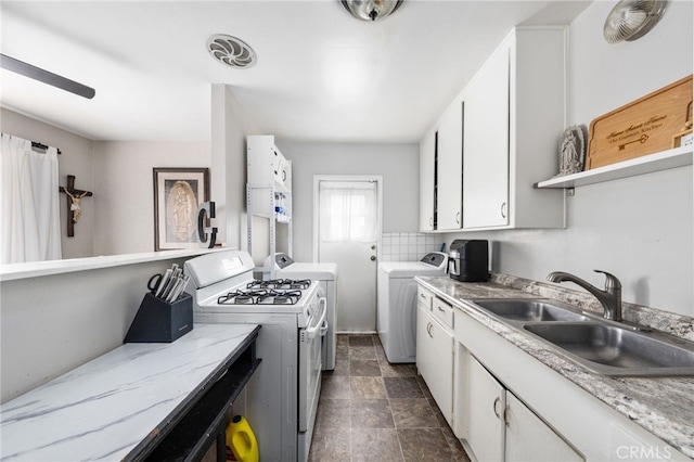 kitchen featuring white cabinetry, sink, tasteful backsplash, and washing machine and clothes dryer