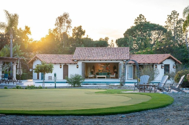 back house at dusk with an outbuilding and a patio area