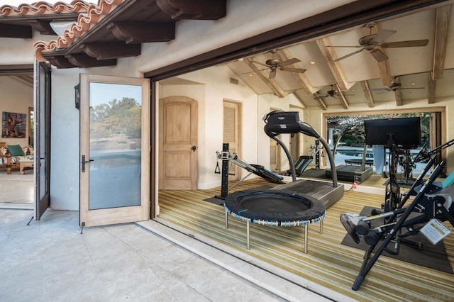 exercise area featuring plenty of natural light, vaulted ceiling, and light tile patterned floors