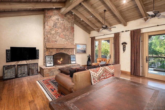 living room featuring wood ceiling, wood-type flooring, a stone fireplace, and ceiling fan