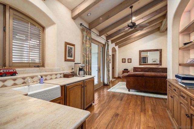 kitchen featuring sink, high vaulted ceiling, light wood-type flooring, beamed ceiling, and ceiling fan