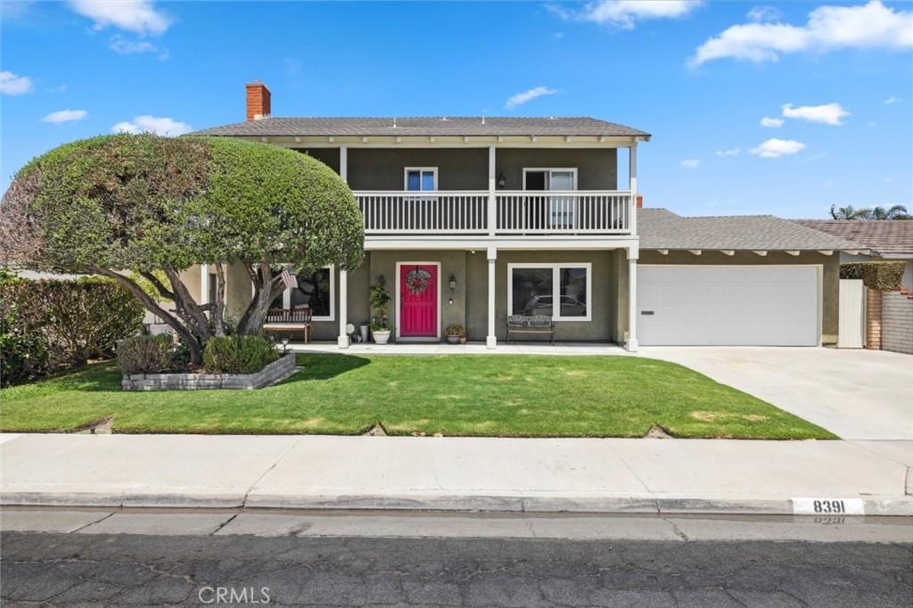 view of front of home with a garage, a front yard, and a balcony