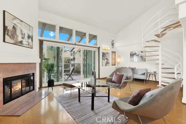 living area with stairs, high vaulted ceiling, wood finished floors, and a high end fireplace