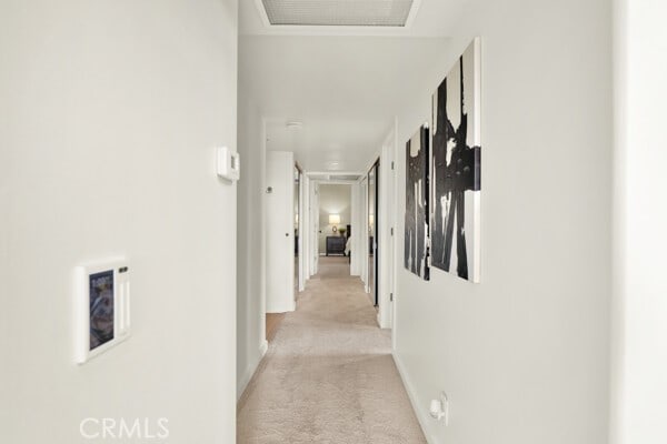 hall with light colored carpet and baseboards