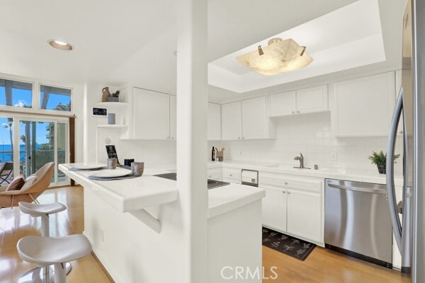 kitchen featuring appliances with stainless steel finishes, a sink, light wood-style floors, and white cabinets