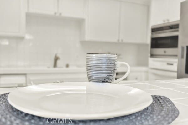 interior details featuring stainless steel oven, white cabinets, and light countertops