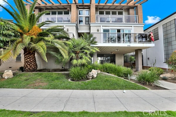 view of front of property featuring a carport, a balcony, and a front yard