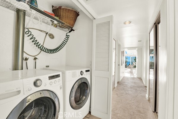 clothes washing area with light carpet, laundry area, and washer and clothes dryer