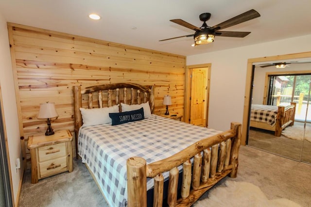 bedroom with wood walls, light carpet, a closet, ceiling fan, and access to exterior