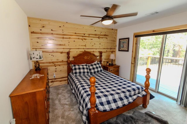 carpeted bedroom featuring ceiling fan, wooden walls, and access to exterior