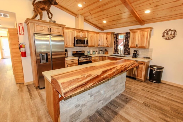 kitchen featuring sink, vaulted ceiling, light hardwood / wood-style flooring, appliances with stainless steel finishes, and decorative backsplash