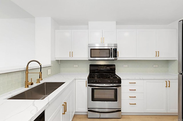 kitchen with appliances with stainless steel finishes, white cabinets, and a sink