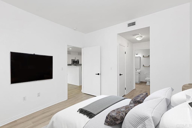 bedroom featuring baseboards, connected bathroom, visible vents, and light wood-style floors