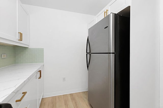 kitchen featuring light wood-style flooring, tasteful backsplash, white cabinets, and freestanding refrigerator