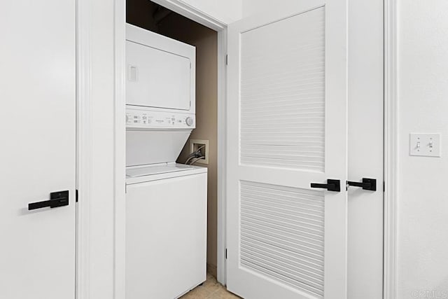 washroom featuring stacked washing maching and dryer, laundry area, and light tile patterned flooring