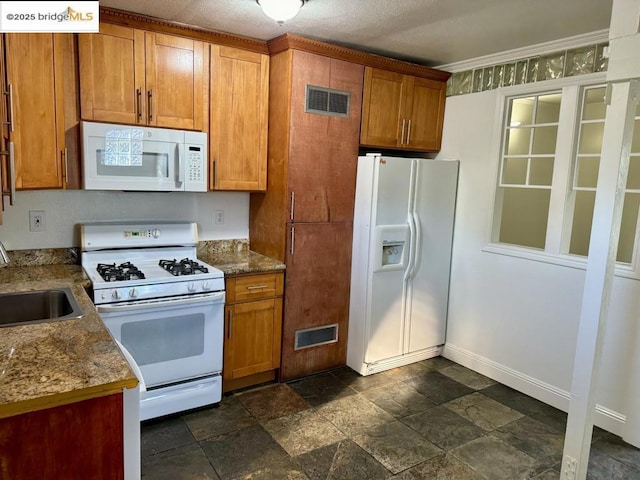 kitchen featuring stone countertops, sink, and white appliances