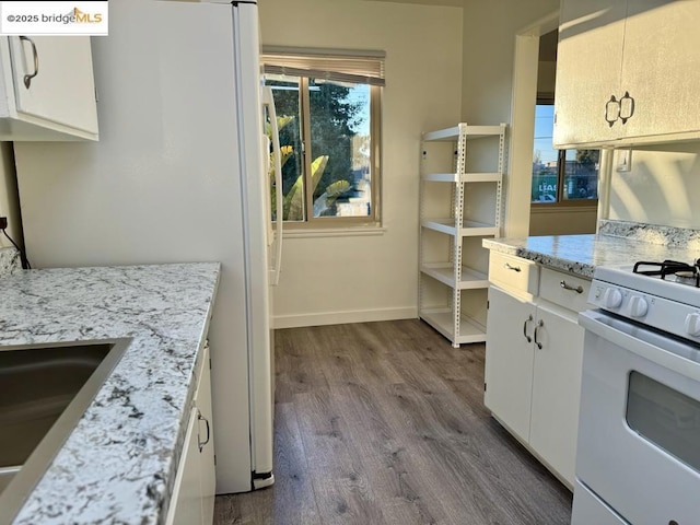 kitchen featuring sink, white appliances, white cabinetry, wood-type flooring, and light stone countertops