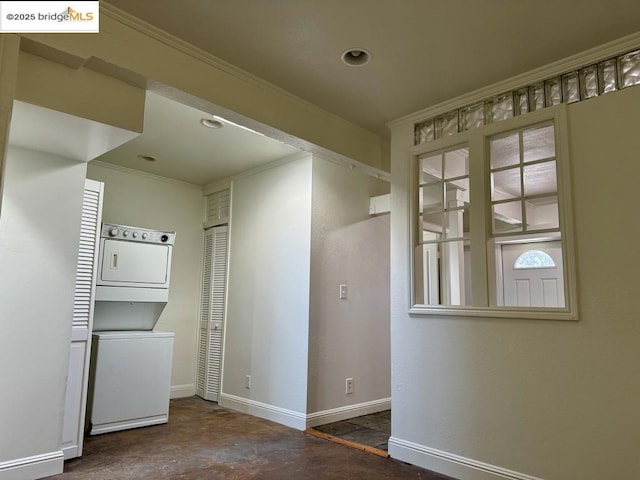 empty room featuring ornamental molding and stacked washer and clothes dryer