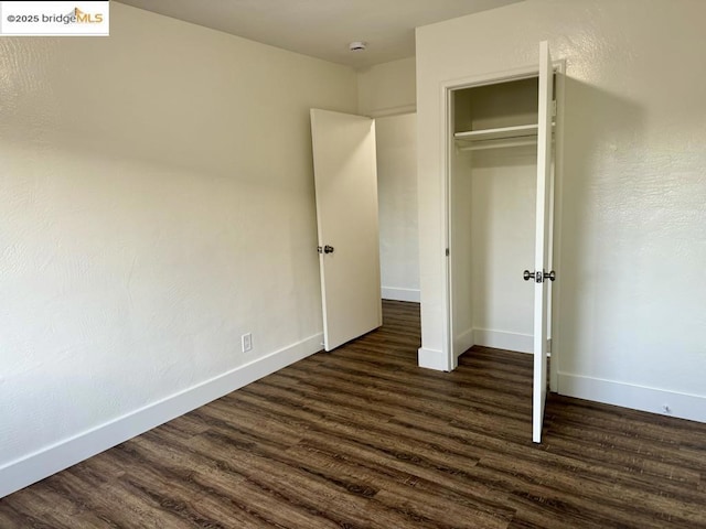 unfurnished bedroom featuring dark wood-type flooring and a closet