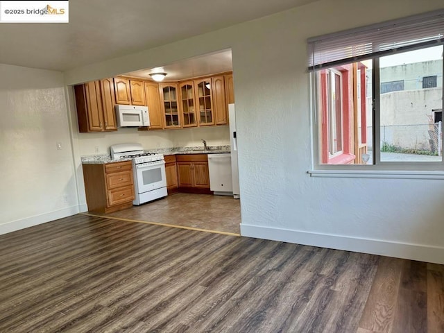 kitchen with dark hardwood / wood-style flooring, sink, white appliances, and light stone counters