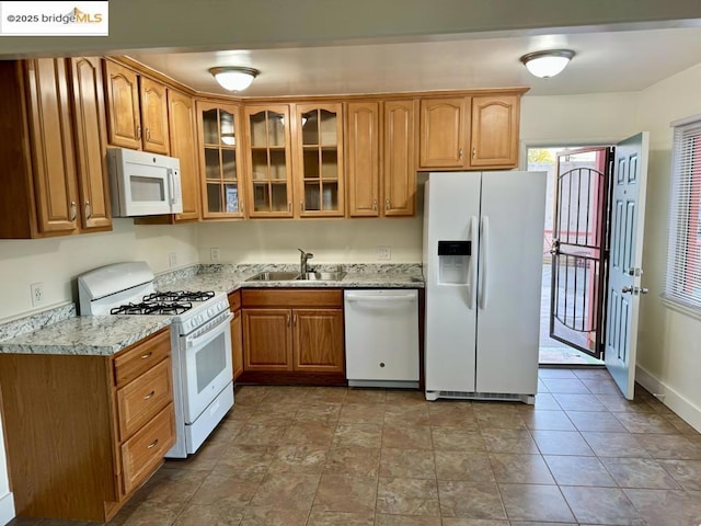 kitchen with white appliances, light stone countertops, and sink