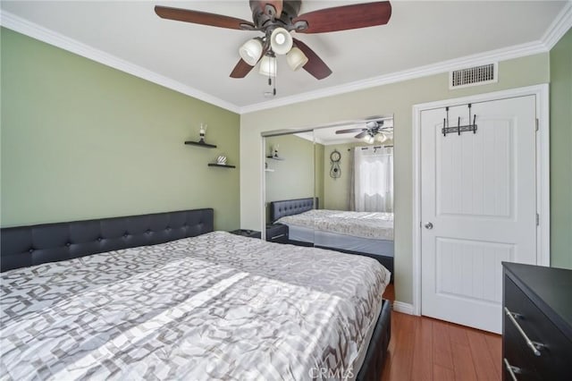 bedroom with dark hardwood / wood-style flooring, ornamental molding, and ceiling fan